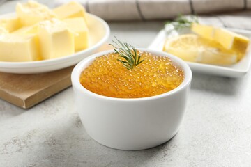 Fresh pike caviar and dill in bowl on light grey table, closeup