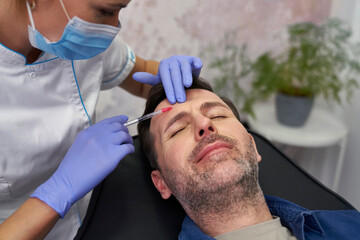 Man having facelifting procedure in beauty salon