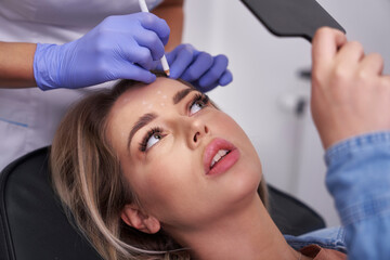 Woman having facelifting procedure in beauty salon