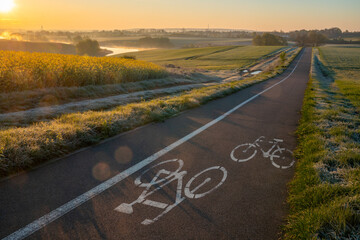 Cycle road running through beautiful spring countryside during foggy, sunny morning