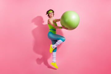 Full size profile portrait of excited sporty fitness instructor jump hands hold fitball isolated on pink color background