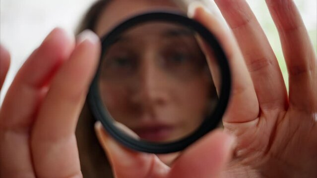 Woman looking through camera lens neutral density nd filter while rotating it