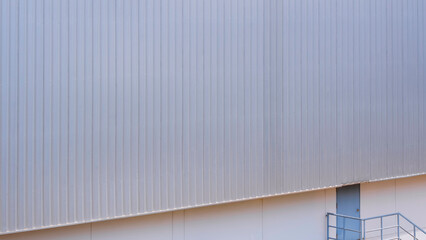 Large aluminium steel wall with a small entrance door on side of large industrial warehouse...