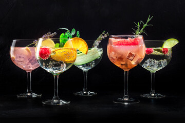 Fancy cocktails with fresh fruit. Gin and tonic drinks with ice at a party, on a black background, a variety