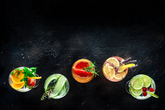 Fancy cocktails with fresh fruit. Gin and tonic drinks with ice at a party, on a black background, shot from the top with copy space