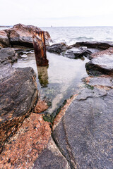 Winter Long Island Sound rocks with metal post