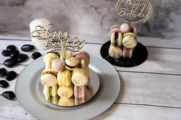 Macaroons in the form of a cake with a candle on a gray background. Happy Birthday.