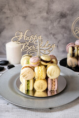 Macaroons in the form of a cake with a candle on a gray background. Happy Birthday.
