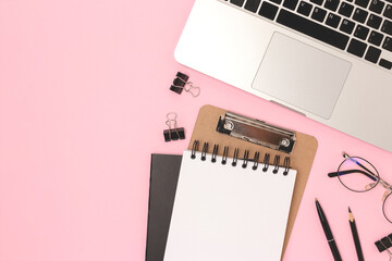 Workspace with laptop, eyeglasses and stationery on a pink background. Business concept with copy space.