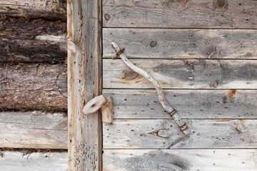 Closup of old wooden door handle and latch on a weathered log wall.