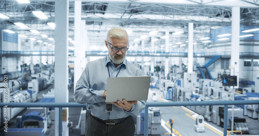 Poster Senior Factory Manager Working on Laptop at a Futuristic Industrial Manufacture with Autonomous AI Robots. Specialist Monitoring All the Data on a Computer, Checking Reports and Planning Workload