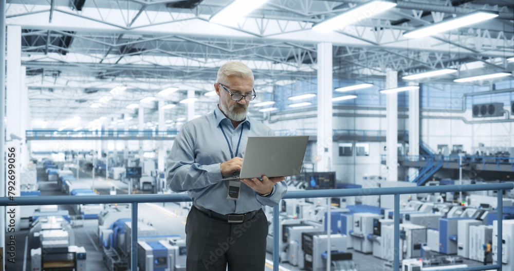 Fototapete Thoughtful Middle Aged Engineer Monitoring and Analyzing Conditions at a Pristine Modern Electronics Factory with Automated Mobility Robots Working with the Help of Artificial Intelligence Software