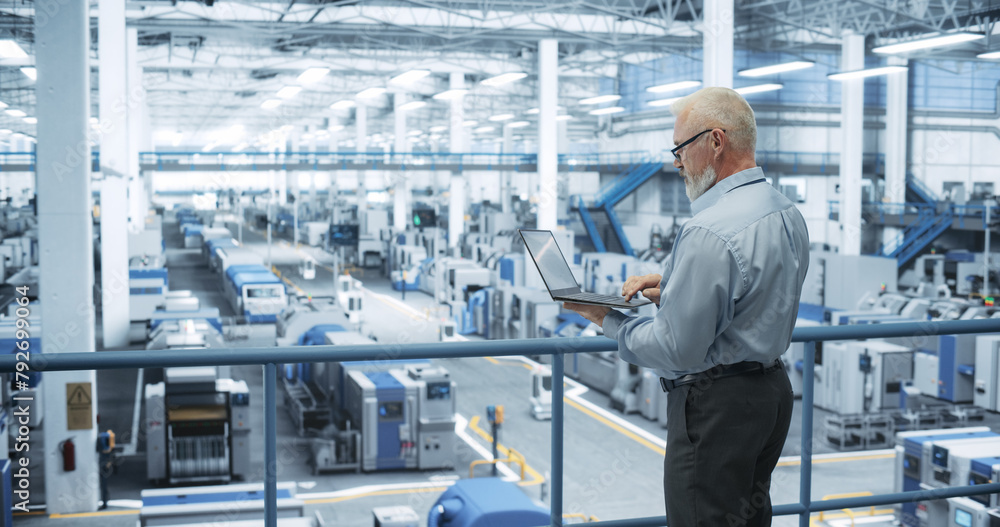 Poster Senior Factory Manager Working on Laptop at a Futuristic Industrial Manufacture with Autonomous AI Robots. Specialist Monitoring All the Data on a Computer, Checking Reports and Planning Workload