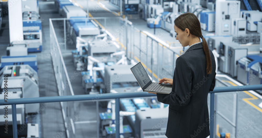 Leinwandbilder portrait of a caucasian female engineer using laptop computer and looking around a factory facility 