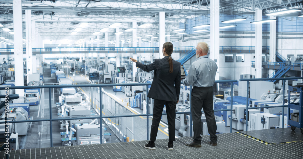 Poster Male Engineer and Female Project Manager Standing on a Platform, Talking, Using Laptop Computer and Monitoring Production at a Modern Automated Electronics Manufacture with AI Robotic Arms