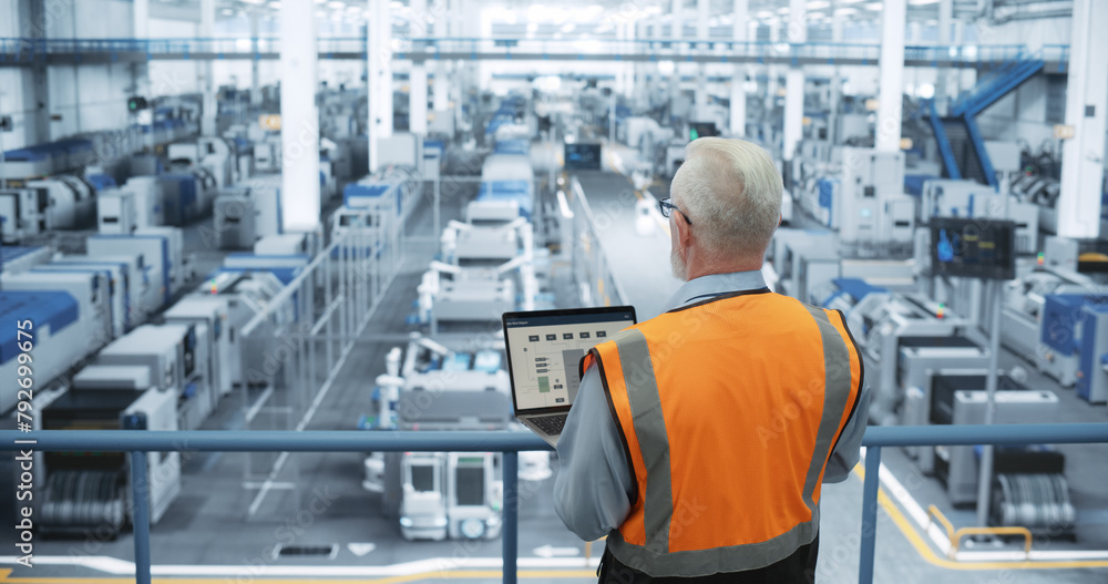 Aufkleber Portrait of a Thoughtful Middle Aged Engineer Monitoring and Analyzing Conditions at a Modern Electronics Factory with Automated Robots Working with the Help of Artificial Intelligence Software