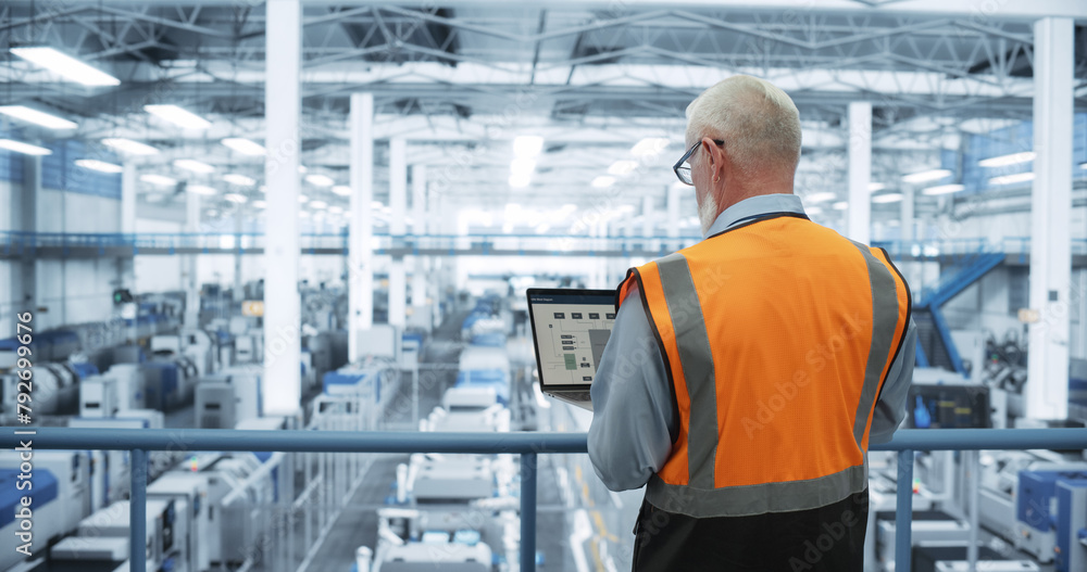 Poster industrial engineer working at a technology factory. middle aged male using laptop computer at work,