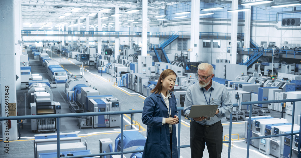 Aufkleber Portrait of a Middle Aged Engineer and Positive Asian Scientist Using Laptop Computer and Talking in a Factory Facility with Equipment Producing Modern Electronic Components for Different Industries