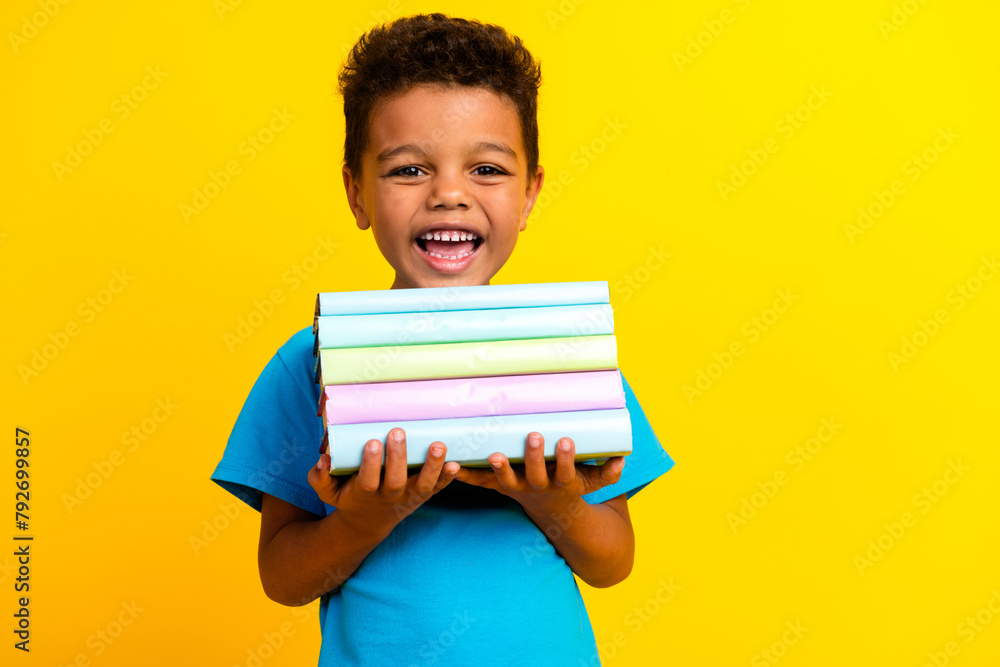 Sticker portrait of positive small schoolboy with afro hair wear blue stylish t-shirt hold book smiling isol