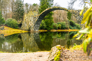 Rakotz Bridge gracefully arches over calm waters, mirrored perfectly against a backdrop of fall foliage. Germany