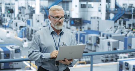 Senior Factory Manager Working on Laptop at a Futuristic Industrial Manufacture with Autonomous AI...
