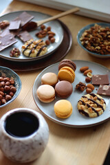 Cup of tea or coffee, cookies, macaroons, chocolate, various nuts and cocoa powder on wooden table. Selective focus.