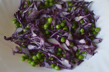 Raw red cabbage salad with green peas and olive oil
