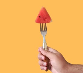 hand holding a fork with a watermelon piece