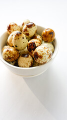 quail eggs in ceramic bowl over white background