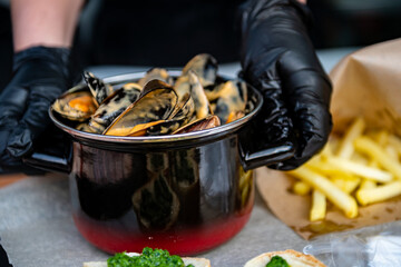 Exquisite mussels in a metal saucepan, complemented by crusty bread soaked in herbs and creamy...