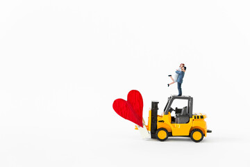 Miniature couple on forklift truck with red heart isolate on white background, love and romance, valentine concept background