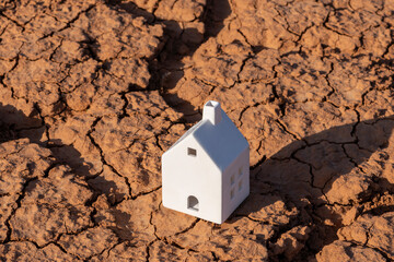 A symbolic ceramic house on heat-cracked clay in the desert