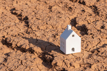 A symbolic ceramic house on heat-cracked clay in the desert
