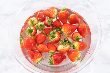Preparing Strawberries in a Glass Mixing Bowl with Water - 792731465