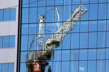 Reflet d'une grue sur une bâtiment vitré sur un chantier de construction	