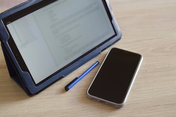 tablet, mobile phone and stylus pen on the wooden table