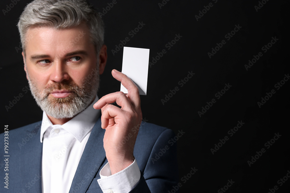 Poster Handsome businessman holding blank business card on black background. Space for text