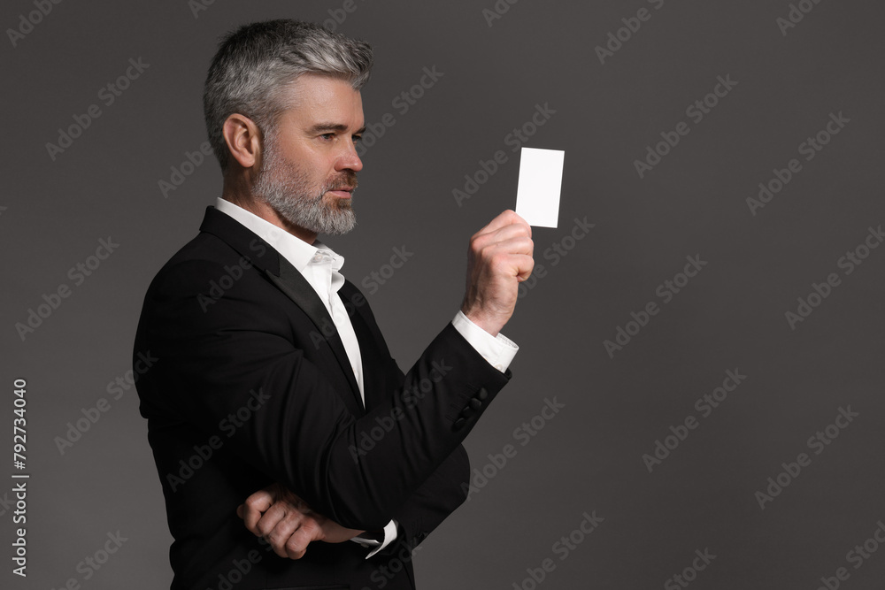 Sticker Handsome businessman holding blank business card on grey background. Space for text