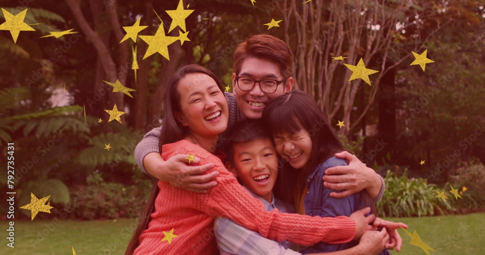 Sticker Image of gold stars over smiling asian parents, son and daughter embracing in garden