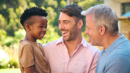 Portrait Of Three Generation Male Family Laughing And Smiling Standing Outdoors In Countryside