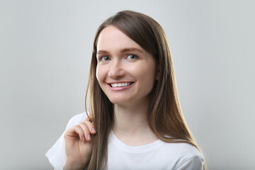 Naklejka premium Portrait of beautiful happy woman on light grey background