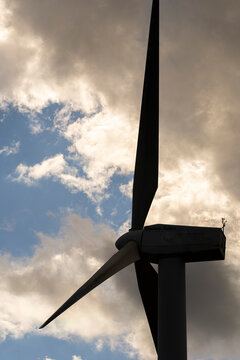This striking image captures a wind turbine in silhouette, set against a dramatic cloudy sky in Catalonia, showcasing Spain's commitment to renewable energy, specifically in Tarragona