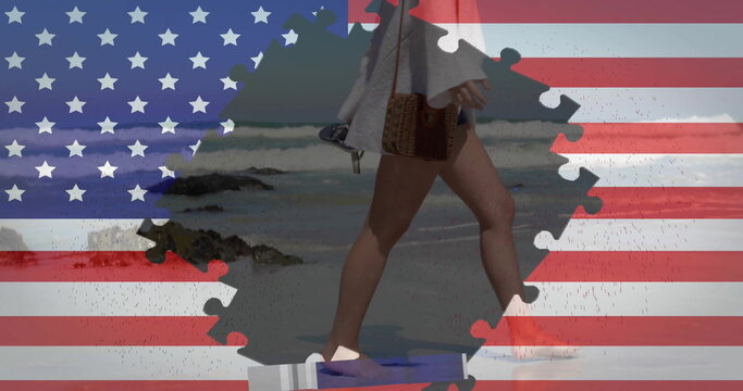 Image of flag of usa with puzzle pieces over caucasian woman walking on beach