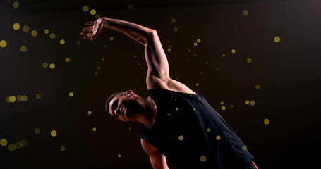 Image of caucasian basketball player stretching and spots of light on black background