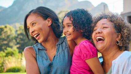 Portrait Of Three Generation Female Family Laughing And Smiling Standing Outdoors In Countryside