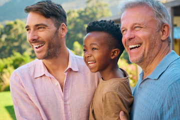 Portrait Of Three Generation Male Family Laughing And Smiling Standing Outdoors In Countryside