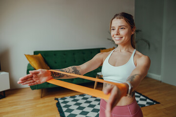 Young woman exercises with resistance band in living room