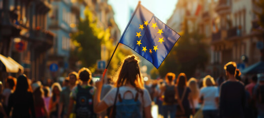 People holding a European flag in a city street at sunset.