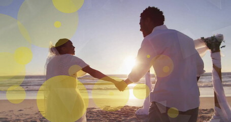 Image of light spots over african american couple getting married on beach