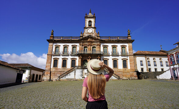 Tourism in Ouro Preto, Brazil. Young tourist woman visiting Tiradentes Square famous landmark of Ouro Preto city, Unesco world heritage site in Minas Gerais state, Brazil.